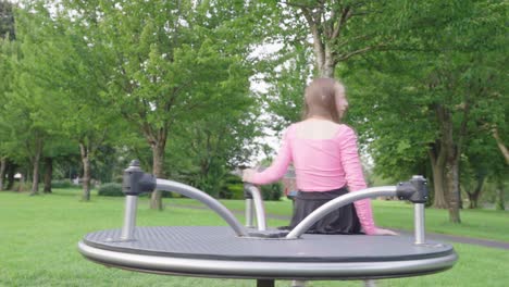 a young girl enjoying being on a merry-go-round at park full of trees