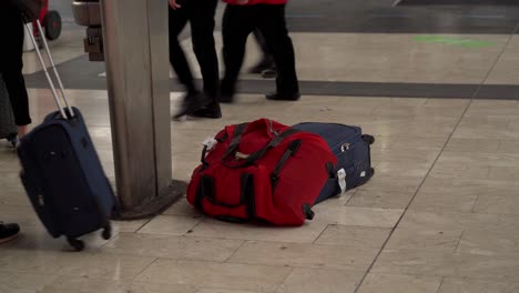 primer plano de equipajes en el vestíbulo de una estación con una mano negra tomando uno