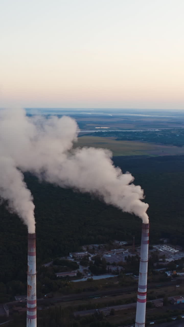 View of pipes with smoke. Power plant with white smoke over blue sky Vertical video