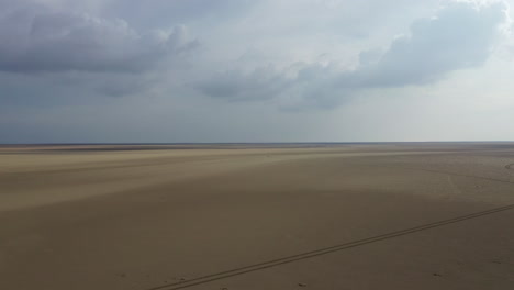 aerial shot over the flat golden sand on the english shore at low tide, bright sunny