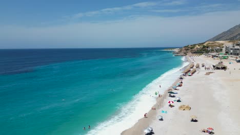 aerial shot of beautiful sandy mediterranean beach with tourists swimming on the shore on a summer day