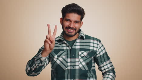 Young-indian-man-showing-victory-sign,-hoping-for-success-and-win,-doing-peace-gesture,-smiling