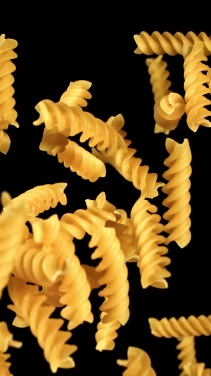 Slow Motion Shot of Fusilli Pasta Falling on Black Background