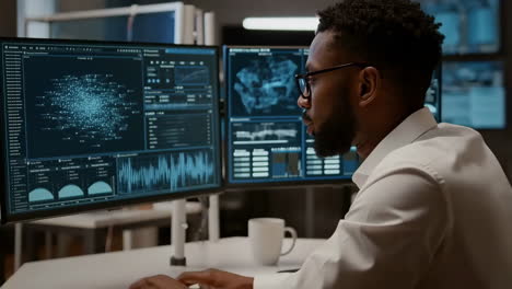 african american data scientist analyzing complex data on multiple monitors