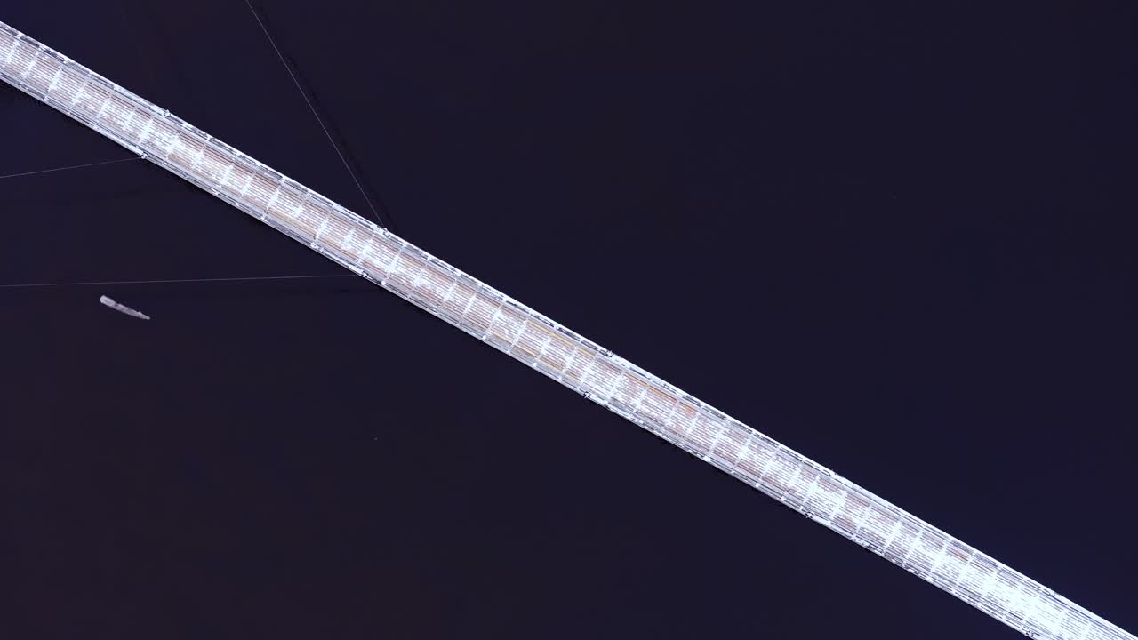 Snowy bridge over deep river, drone hovers still, ice slowly drifts below