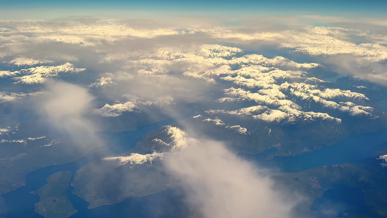 Vista aerea di montagne innevate e nuvole in pieno giorno, una scena maestosa.