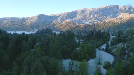 una vista impresionante de la montaña cubierta de nieve que se eleva sobre el bosque envuelto en niebla en el valle y el camino sinuoso