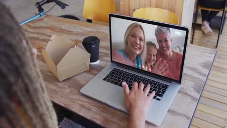 Frau-Isst-Einen-Snack,-Während-Sie-Im-Café-Einen-Videoanruf-Auf-Dem-Laptop-Führt