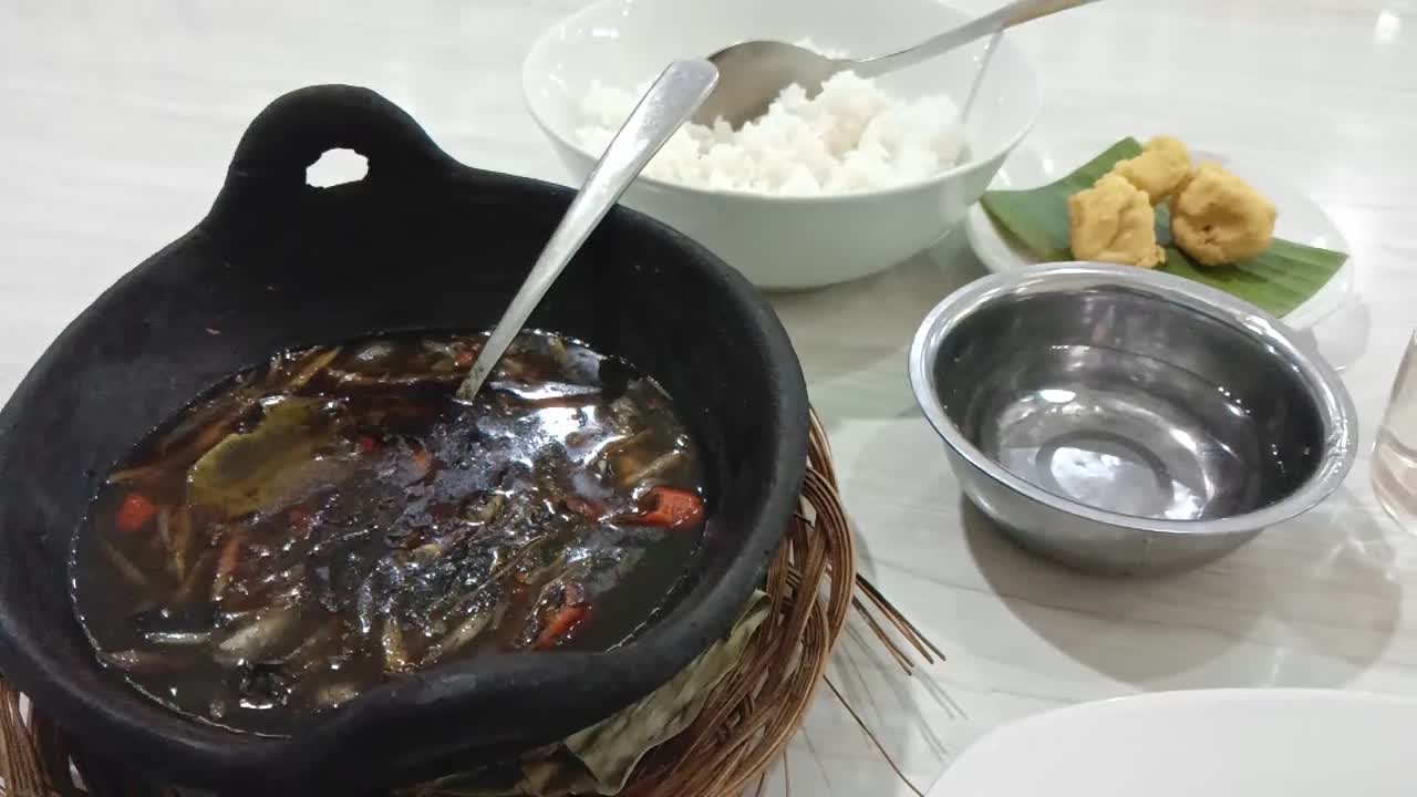 Squid cooked Mandar typical of West Sulawesi province. Squid in black ink sauce with spicy seasoning. Indonesian home cooking menu with chili, ginger, and lime leaf seasoning served in a large pot.