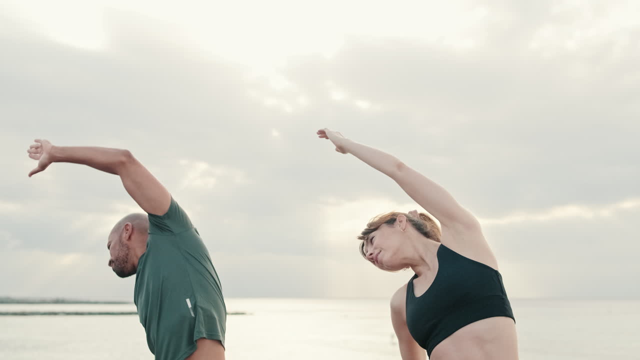 Coppia che fa stretching ed esercizio all'aperto in riva al mare