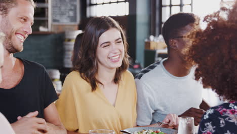 group of friends meeting for meal in restaurant sitting around table talking