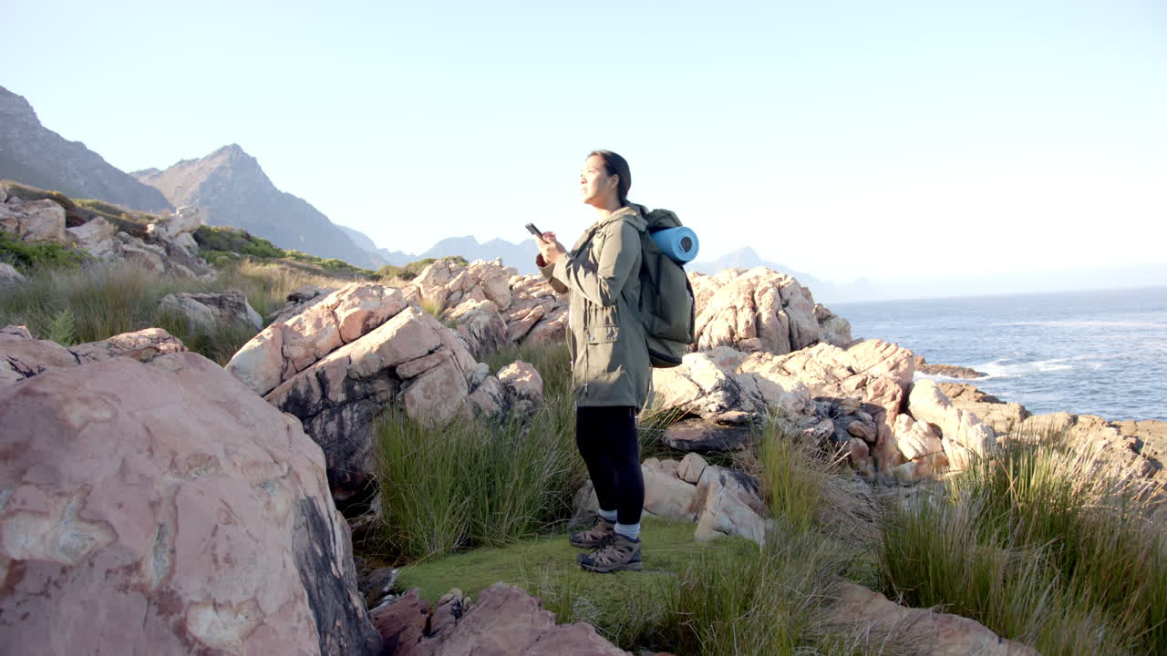 Hiking in mountains, woman with backpack and yoga mat enjoying scenic view