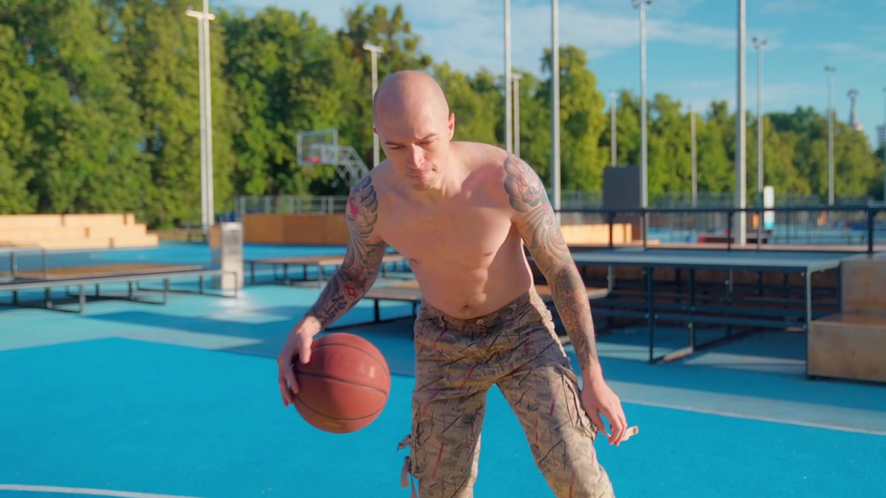 Uomo calvo atletico che palleggia a basket su un campo all'aperto