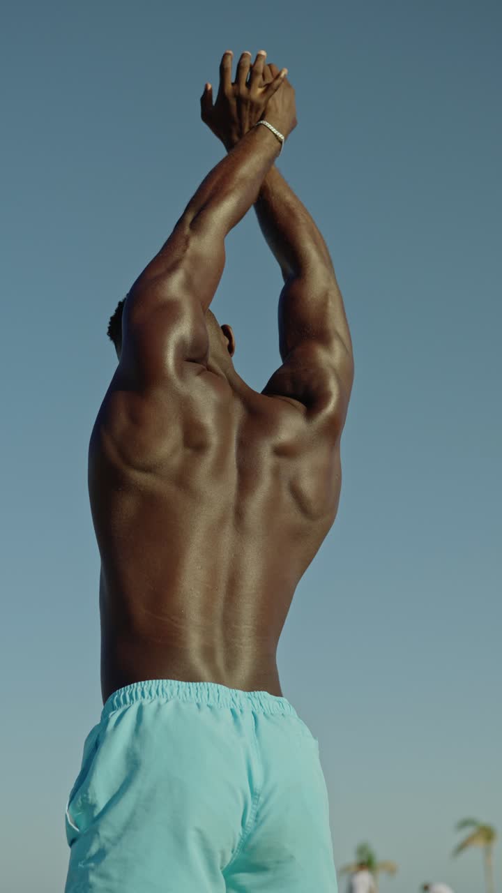 Muscular man stretching on the beach
