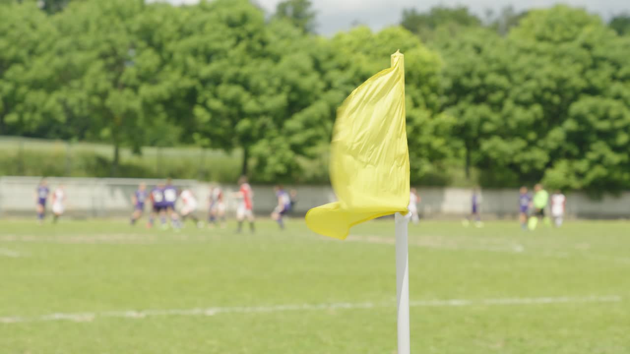 una bandera de esquina amarilla ondeando en el viento en un campo de fútbol, equipos de fútbol femenino jugando