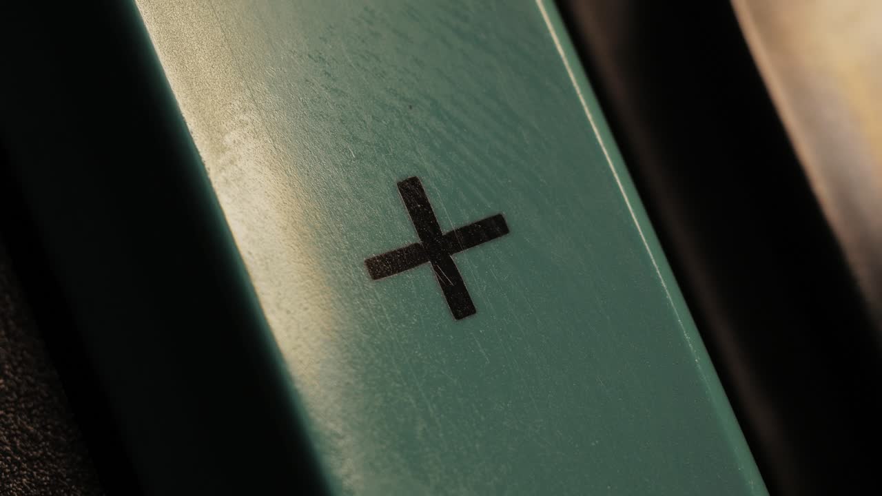 Close up of a finger pressing a green plus button in low light