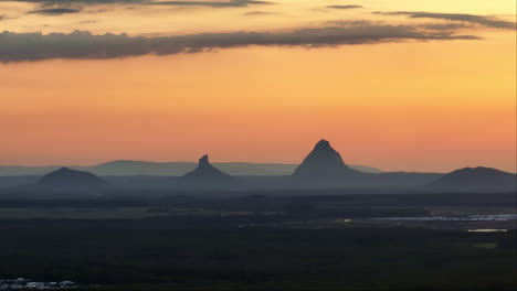 Bright-Orange-Sunset-With-Glasshouse-Mountains-On-Horizon,-Sunshine-Coast-Telephoto-4K-Drone