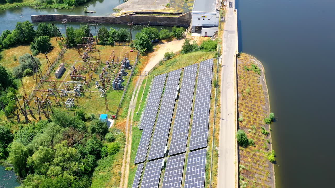 Solar power station near the river at sunlight. Photovoltaic solar cells generate clean energy from the sun on a modern solar farm. Aerial view.