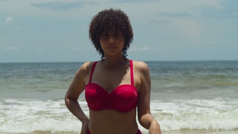 on a sunny day, a young girl with curly hair enjoys the tropical island beach in a red bikini