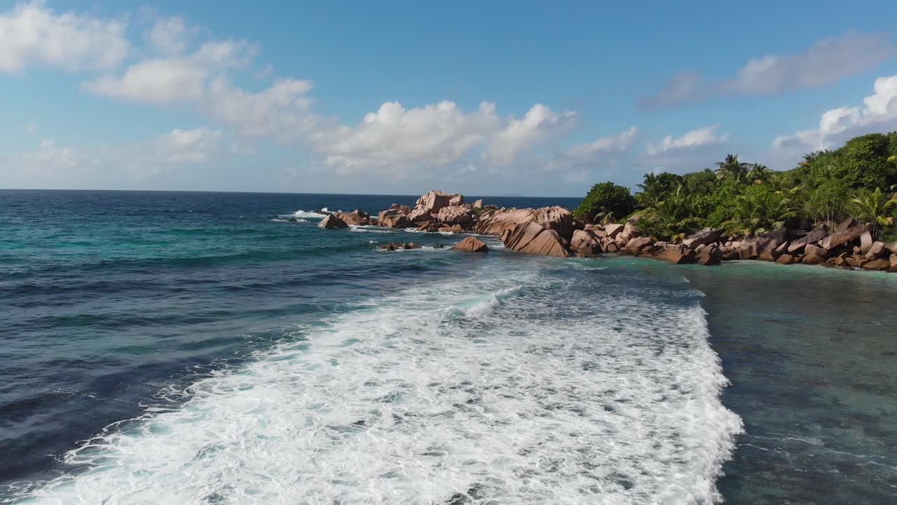 vista aérea siguiendo las olas rodando hacia las playas blancas y despobladas de anse coco, petit anse y grand anse en la digue, una isla de las seychelles