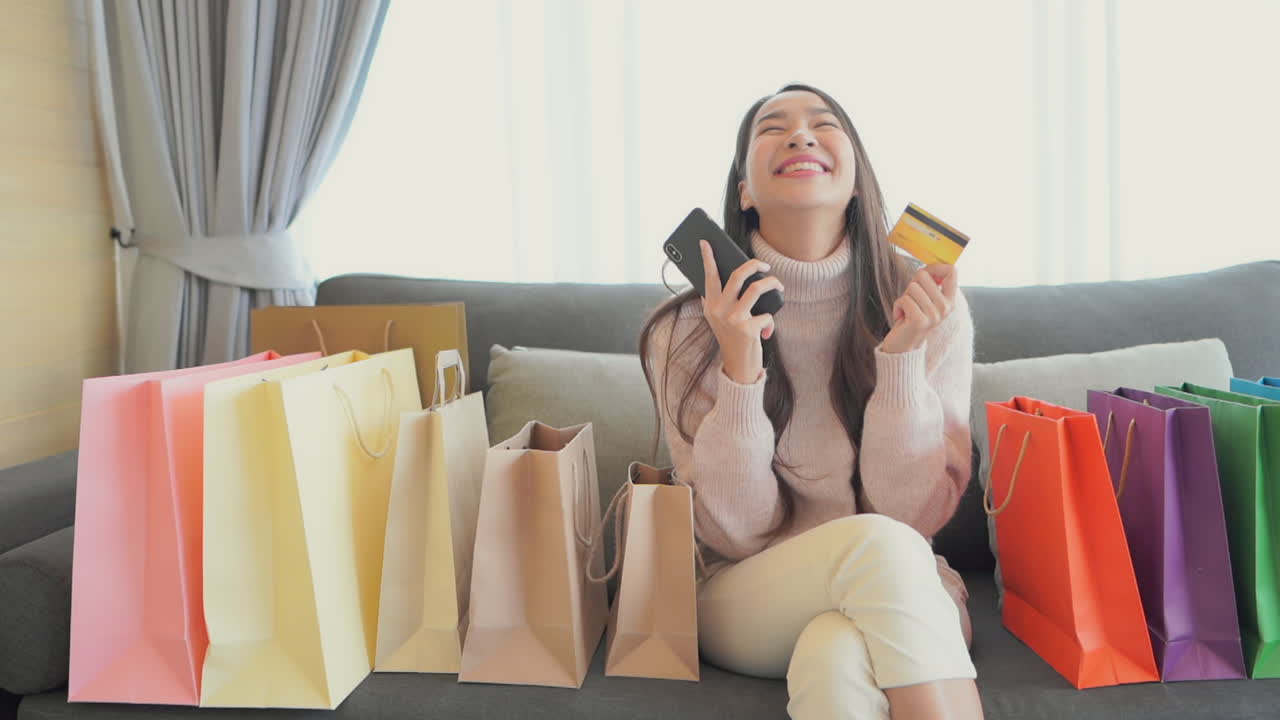 A young woman surrounded by colorful shopping bags, while shopping online reacts to a successful transaction