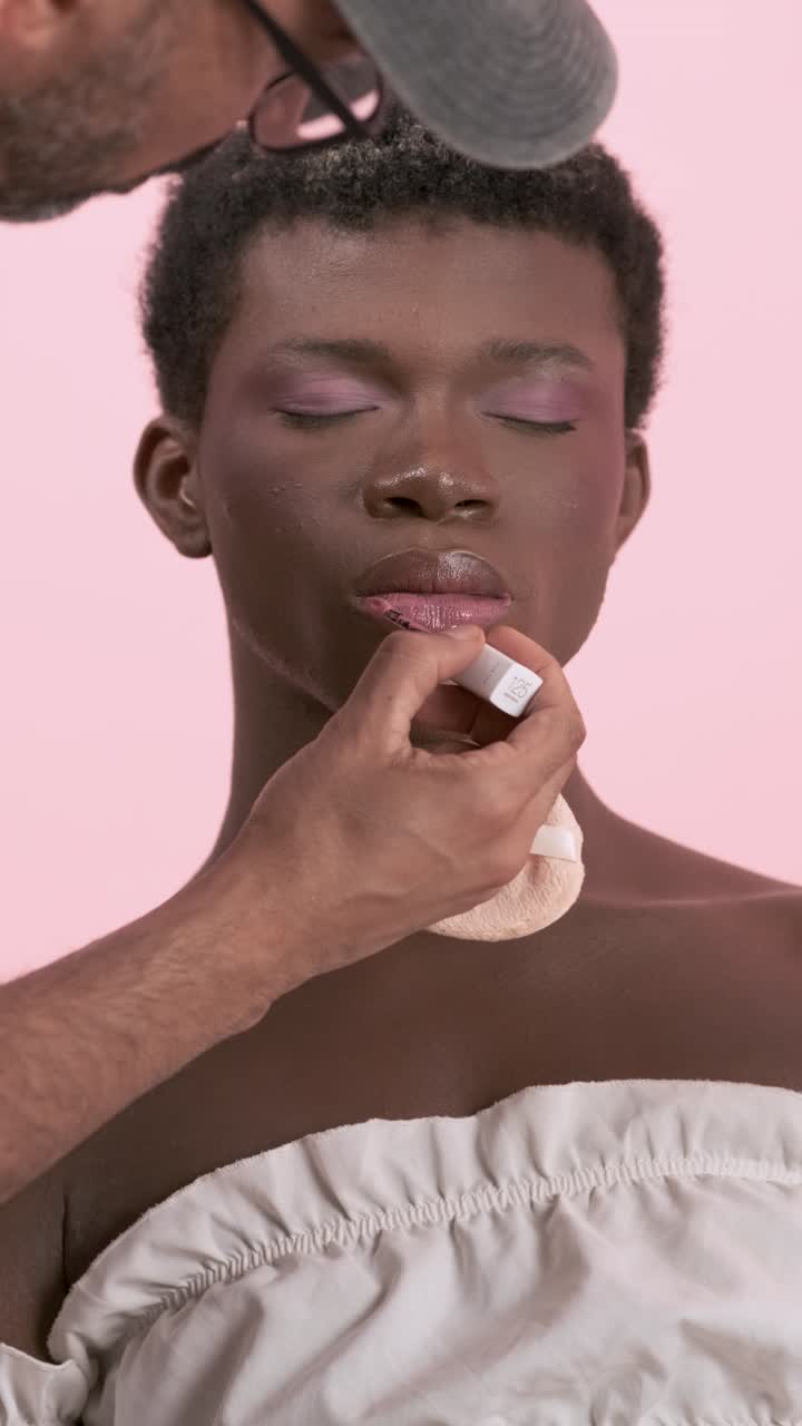 Frontal view of a stylist making up a transgender person