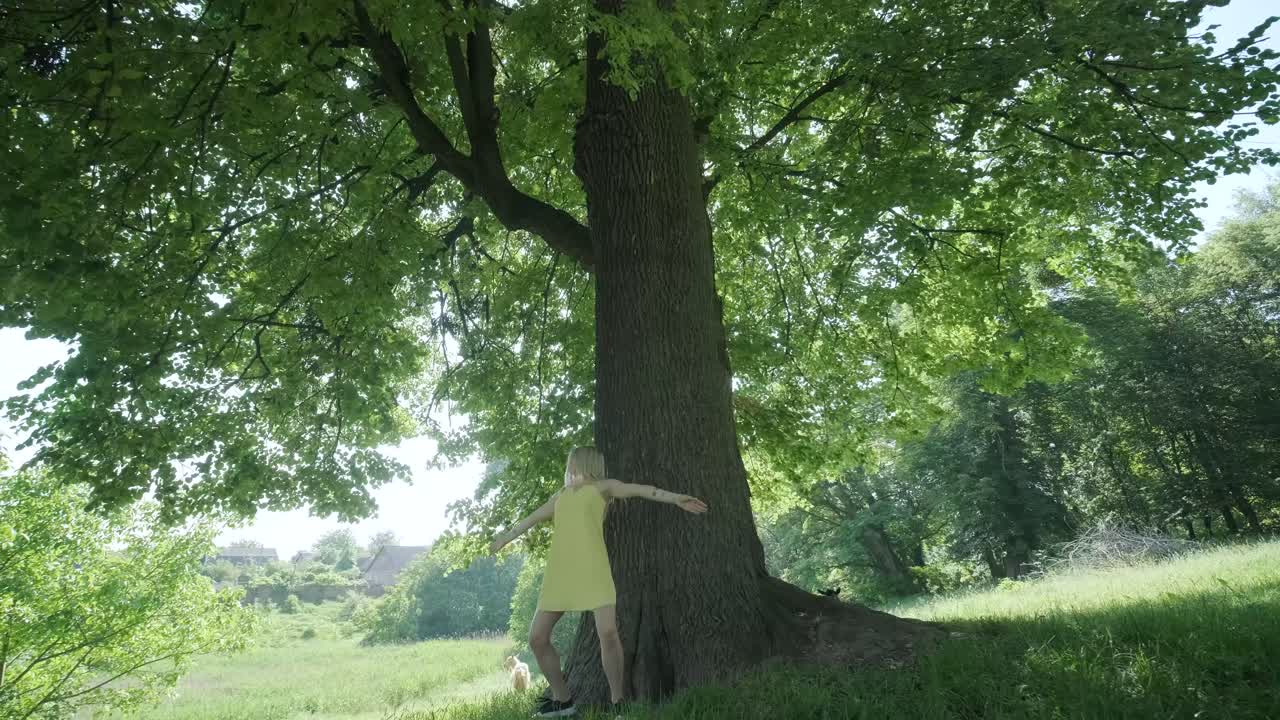 Woman in Yellow Dress Dancing by Tree in Summer Park