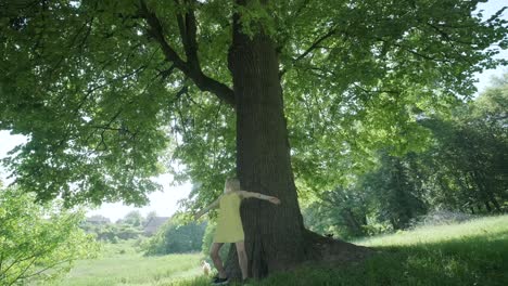 woman in yellow dress dancing by tree in summer park