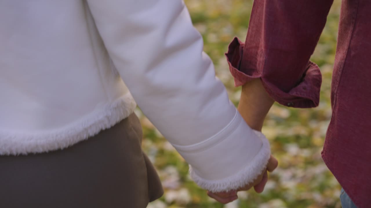 a couple holding hands while walking around in the park.