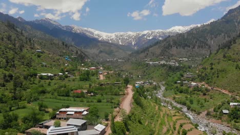 aerial over road through swat valley with snow capped mountains in distance