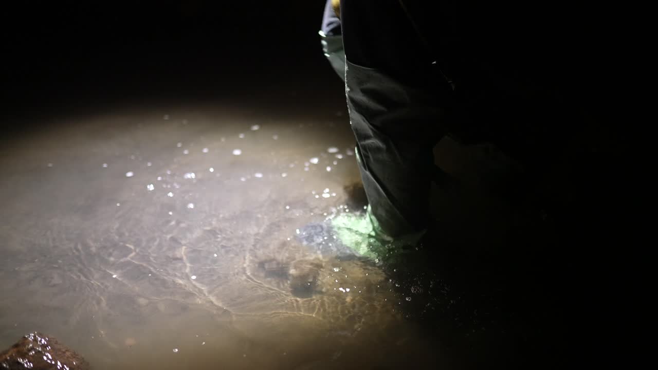 persona navegando con botas en un cuerpo de agua oscuro por la noche.