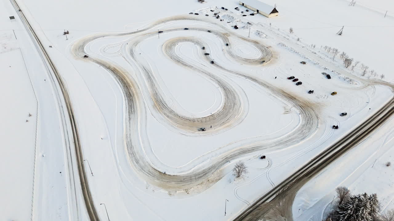 Panoramic drone shot around rally cars driving on a ice track, sunny, winter day