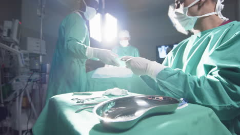 diversos cirujanos que utilizan instrumentos quirúrgicos en el quirófano del hospital, en cámara lenta