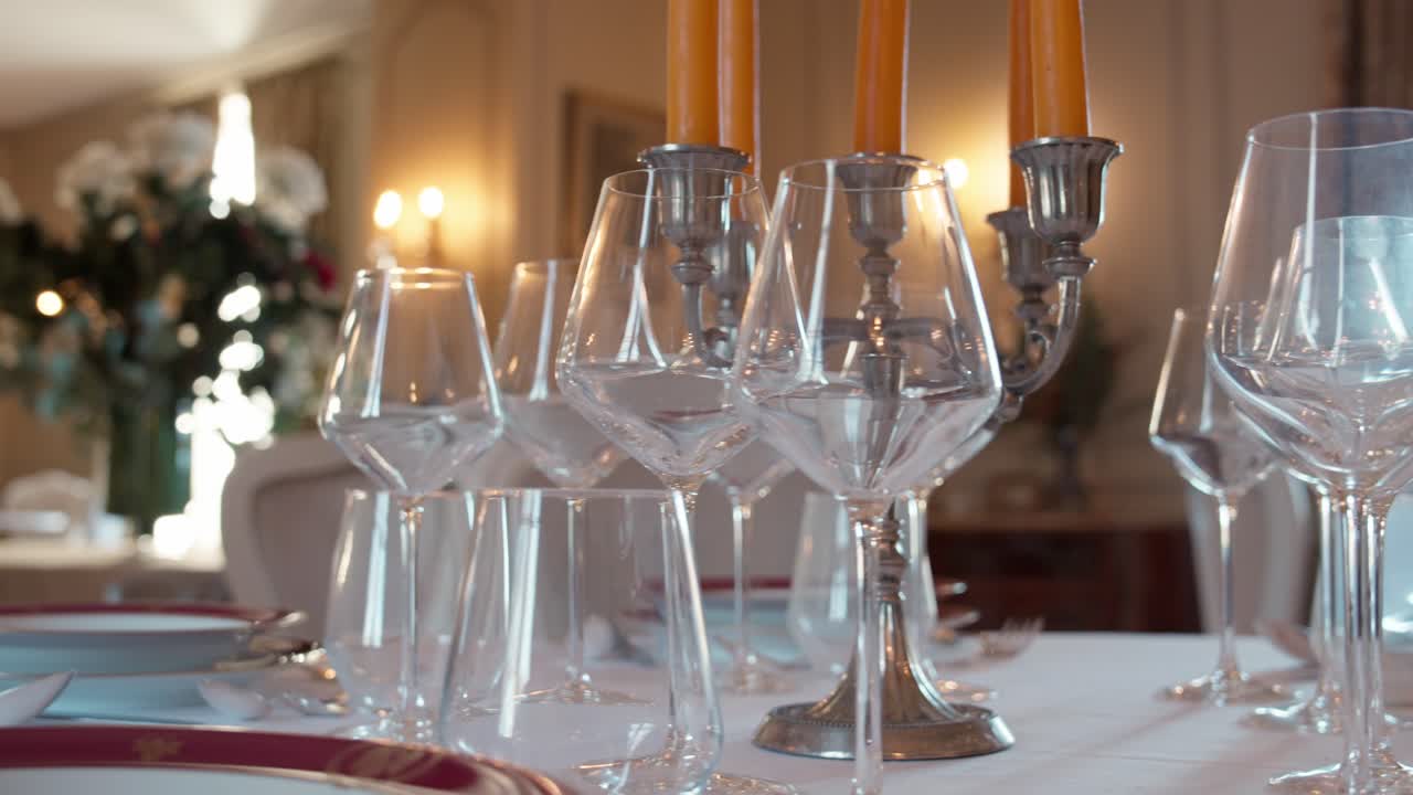 Crystal glassware arranged for a banquet or dinner party with blurred warm candlelight in the background