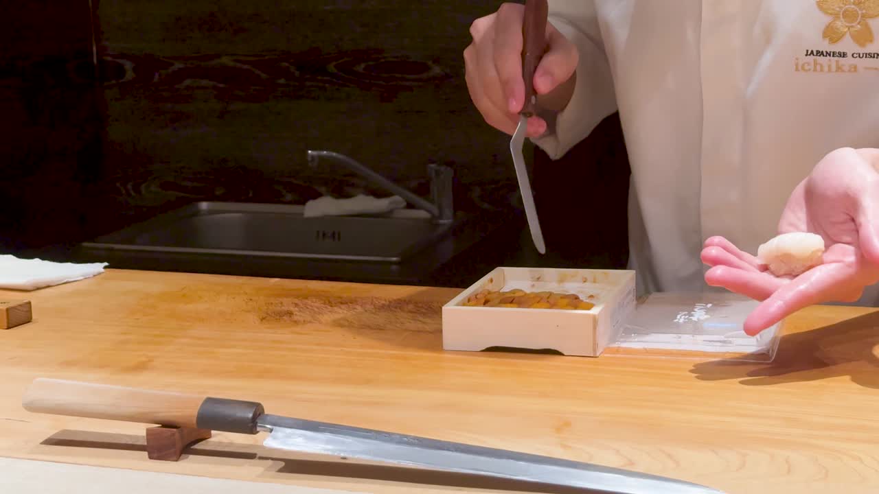 Chef prepara con maestria sushi nigiri di uni