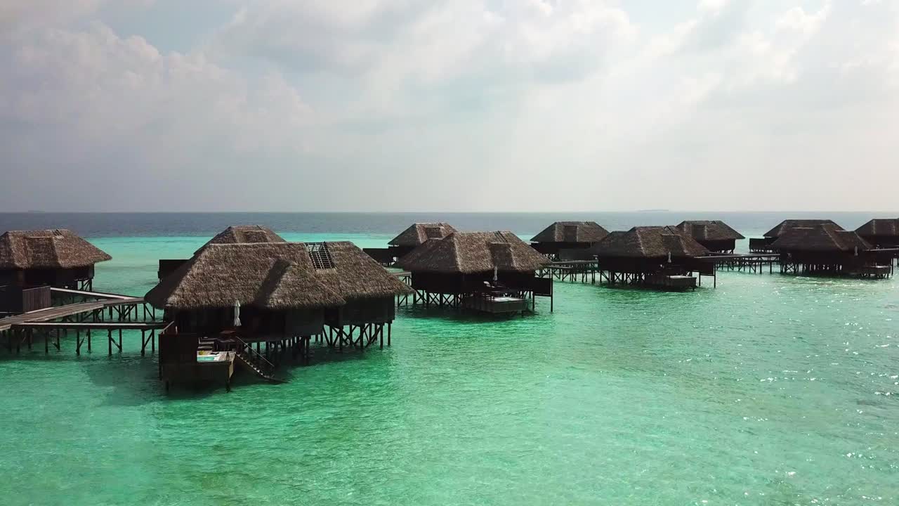 Aerial, rising, drone shot, tilting over villas, in swallow, turquoise sea, on a sunny day, on the Conrad Rangali island, in Maldives