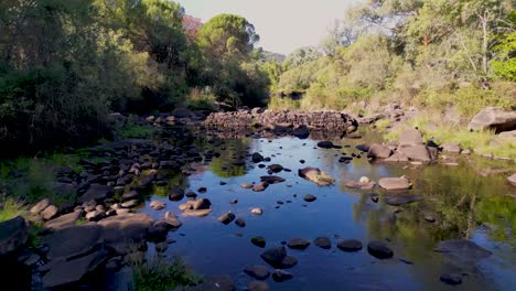 Drone-flies-low-over-rocky-river-bed-in-Sierra-de-Andujar-landscape-Spain