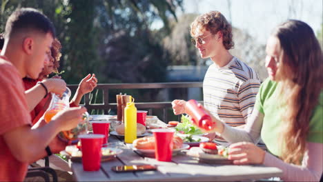 a group of young people enjoying a meal together outdoors