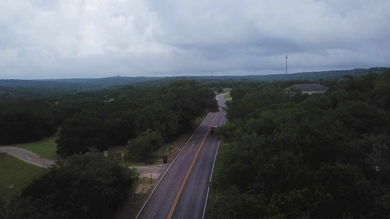 Aerial drone shot of black SUV driving through the bush