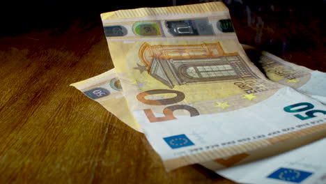 close up of hands counting 50 euro money banknotes, wooden table, static, slow