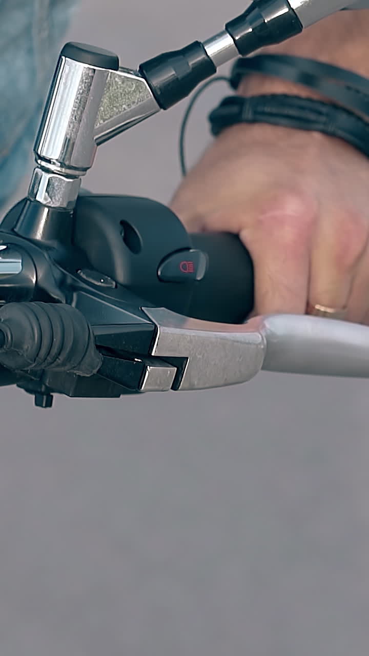 closeup man in denim shorts sits on motorcycle holding black and metal handlebars on gray road
