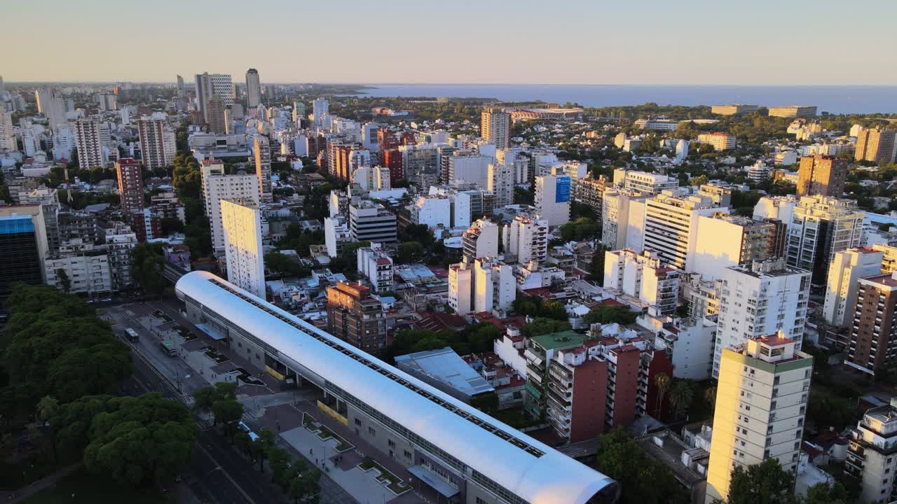 vuelo orbital sobre la estación de tren del barrio de belgrano con el río de la plata al fondo, buenos aires, argentina