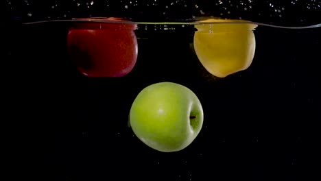 beautiful green apple being dropped into water in slow motion