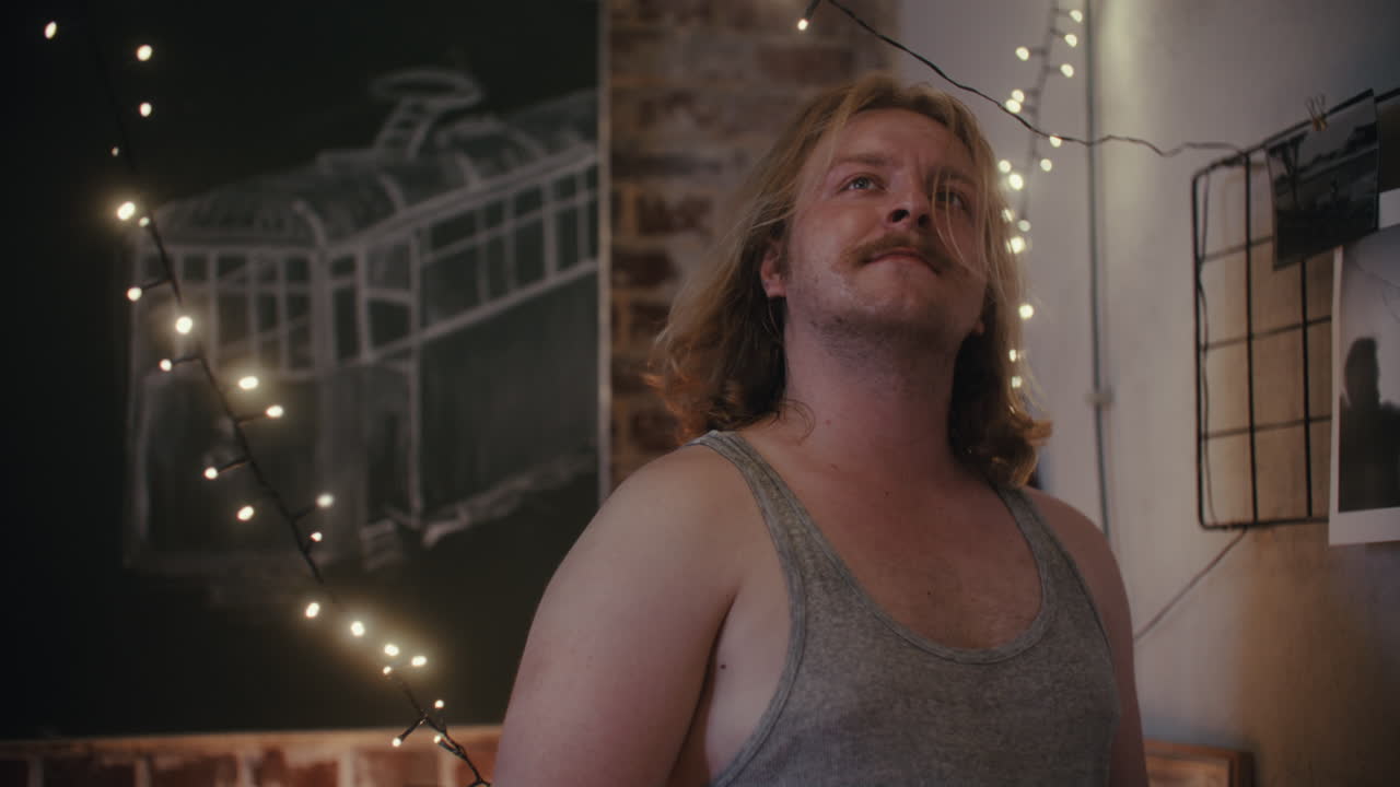 Man in a Room with String Lights and Artwork