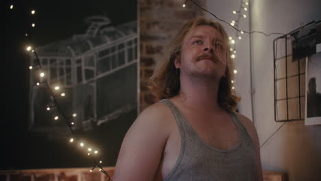 man in a room with string lights and artwork