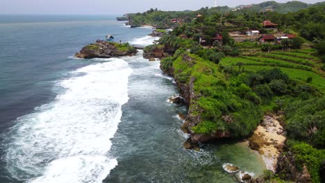 Aerial-view-of-coastline-with-cliffs-that-are-hits-by-the-wave---Tropical-beach-on-the-south-of-Java-Island,-Yogyakarta,-Indonesia