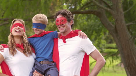 boom text on speech bubbles against mother and dad carrying their son in superhero costume