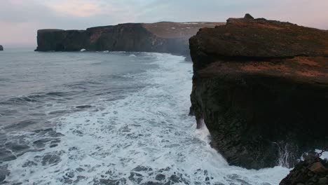 las olas fuertes se estrellan contra los acantilados escarpados de dyrholaey, cerca de vik, en islandia.