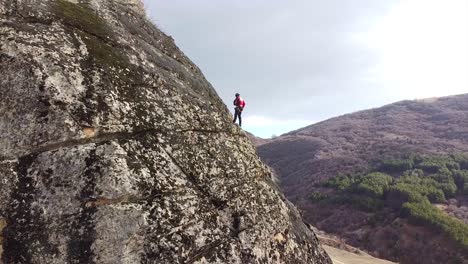 Climber-standing-on-a-rock-securing-his-equipment-drone-shot