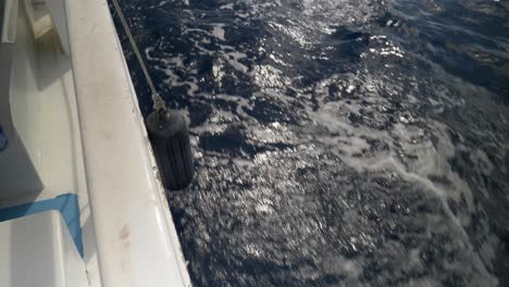 Boat-on-blue-ocean-with-gentle-waves-and-sunlight-reflecting-on-the-water